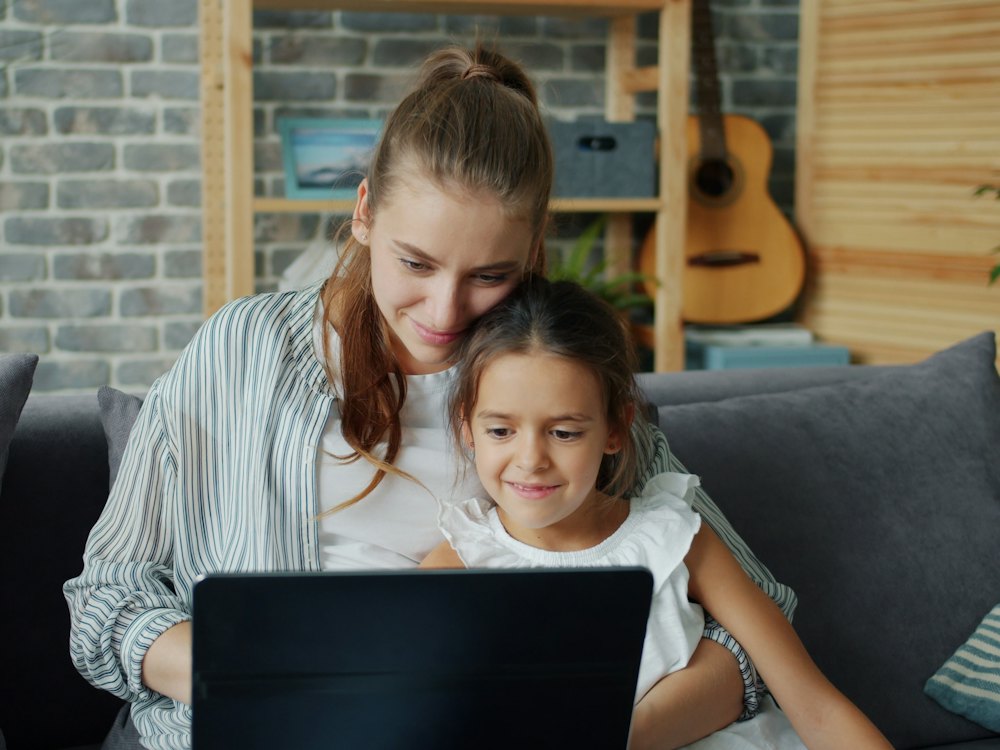 Mamma e figlia sul divano davanti al portatile